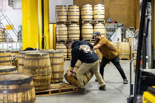 Workers at Detroit City Distillery pushing barrels